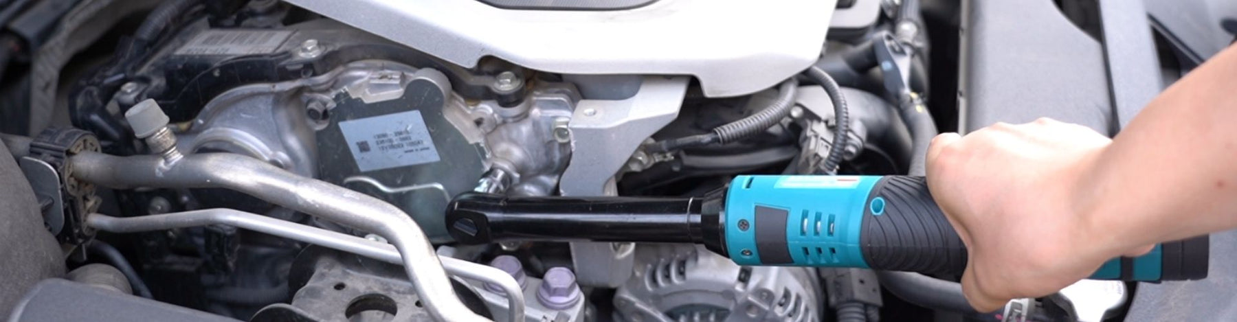 Close-up of a hand operating a Seesii cordless ratchet wrench during car engine repair.